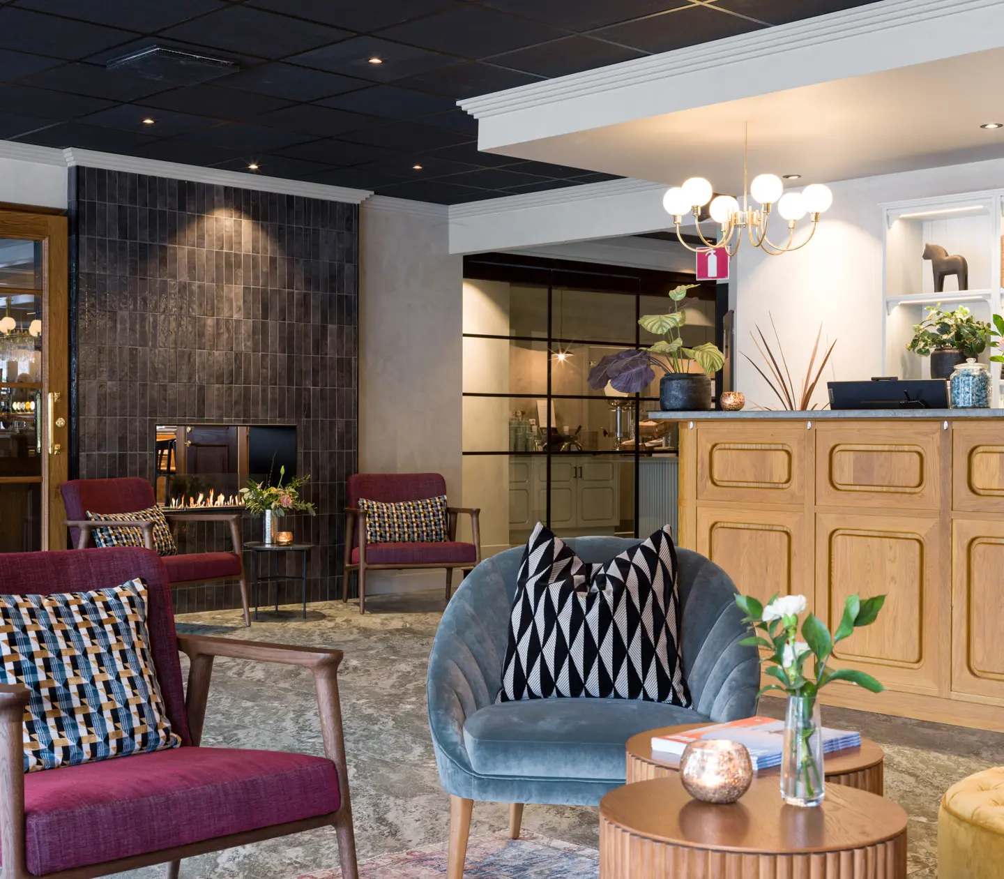 Cozy hotel lobby with armchairs, fireplace and plants