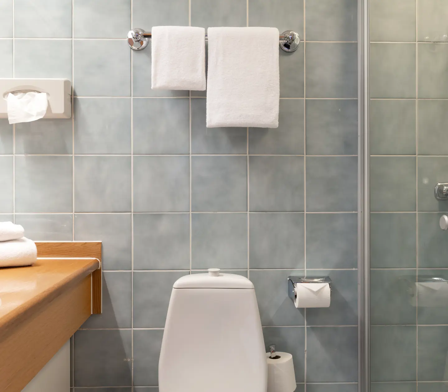 Blue tiled bathroom with toilet, shower and sink