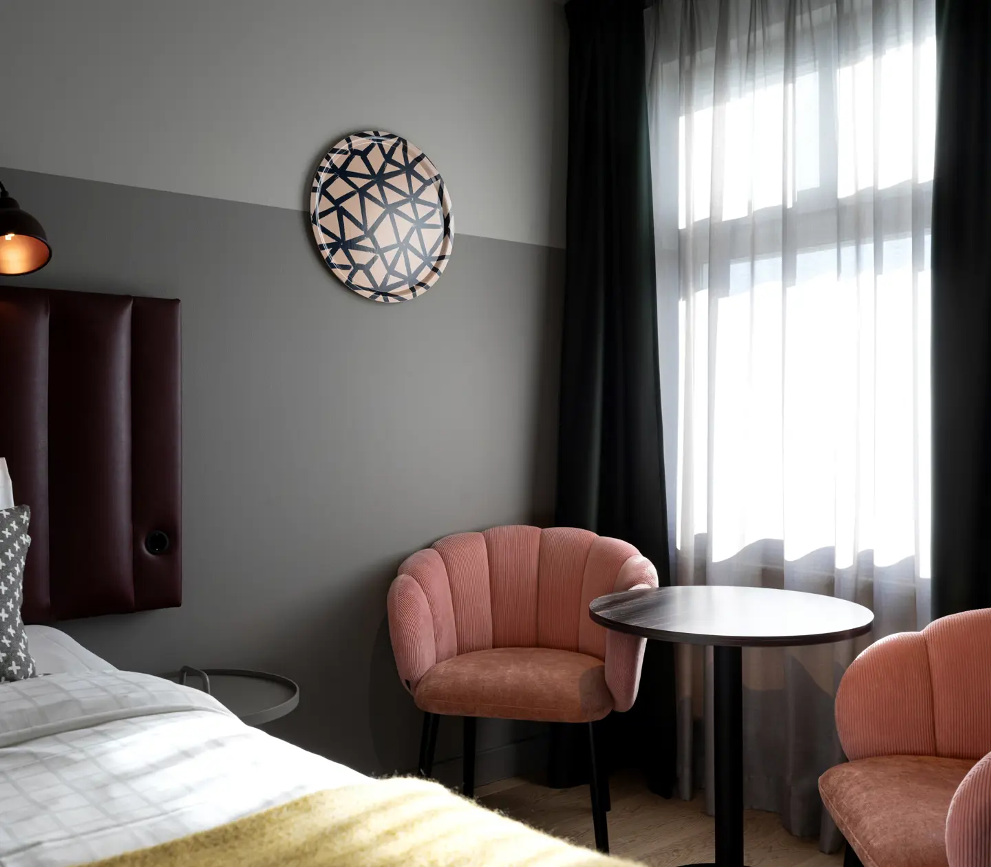 Hotel room with double bed, pink armchairs and window