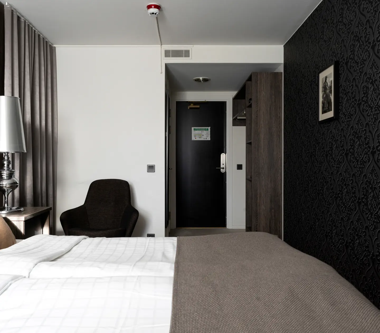 Hotel room with double bed, armchair and lamp
