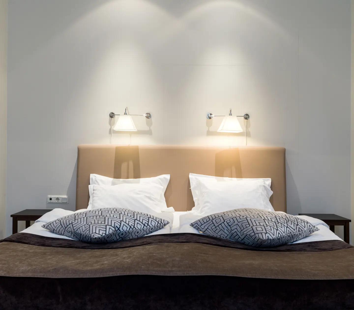 Bright suite with bed, bedside lamps and blue-patterned pillows